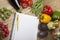 Vegetables with book and pen on wooden surface