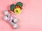 Vegetables  capsicum, broccoli and tomato in heart shape plate, pink dumbbells and measuring tape  on pink background with copy
