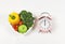 Vegetables  capsicum, broccoli, tomatoes and apple  in heart shape plate  on white background with pink vintage alarm clock,