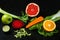 Vegetables and fruits healthy food dropping out on dark background. Fresh orange, apple, lime, carrot, salad, beet and
