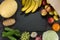 Vegetables and fruits potato cabbage banana melon grape cucumbers onion garlic orange apples pear a dark background. Free space