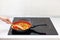 Vegetables are in a frying pan. Woman cooking colourful fresh vegetables on an electric stove.