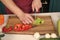 Vegetables getting cut on wooden cutting board. Hand slice green salad with ceramic knife. Hands cut vegetables with