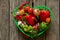 Vegetables in a green basket on a wooden table in the kitchen, tomatoes red pepper garlic close up