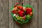 Vegetables in a green basket on a wooden table in the kitchen, tomatoes red pepper garlic close up