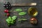 Vegetables and herbs on dark rustic wooden background. Greek black olives, fresh green sage, rosemary, basil herbs, oil