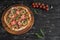 Vegetables, mushrooms and tomatoes pizza on a black wooden background