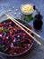 Vegetables salad with purple cabbage, carrot, sprouted mung, parsley on grey clay plate on dark background. Cole Slaw Salad of red