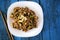 Vegetables with soya souce decorated with cashew nuts on blue rustic table with sticks.