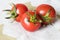 Vegetables on the table, three tomatoes on the white table cloth