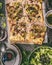 Vegetables tart with leek, served with green salad and dressing on rustic kitchen table background, top view.