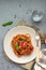 Vegetarian appetizing pasta served with tomato sauce, basil and fresh cherry tomatoes on ceramic plate.