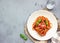 Vegetarian appetizing pasta served with tomato sauce, basil and fresh cherry tomatoes on ceramic plate.