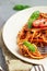Vegetarian appetizing pasta served with tomato sauce, basil and fresh cherry tomatoes on ceramic plate.