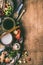 Vegetarian asian cooking ingredients with chopsticks, coconut milk, soy sauce, chopped spices and vegetables on rustic wooden