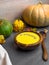 Vegetarian autumn cream soup with seeds, Pumpkin and carrot soup, wooden bowland colorful autumn foliage, side view
