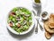 Vegetarian avocado, vegetables, feta cheese salad and grilled bread - delicious healthy lunch, snack on a light background, top