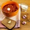 Vegetarian borsch in an orange bowl, sour cream, garlic, rustic bread on a wooden background. Vegetarian food. Healthy lifestyle
