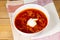 Vegetarian borsch in a white bowl, sour cream, garlic and fresh rustic bread on a wooden table. Vegetarian food. Healthy lifestyle