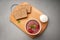 Vegetarian borscht in a disposable dish for delivery near sour cream and bread on a wooden Board top view