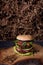 Vegetarian burger with falafel patty on rustic wooden board, hay straw texture background.