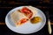 Vegetarian burrito with fresh vegetables on the white plate decorated with silver fork on black wooden kitchen background