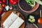 Vegetarian burrito on wooden board over black table surrounded by ingredients.