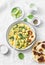 Vegetarian chickpea, spinach, potato curry plate and naan flatbread on white background, top view.