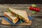 Vegetarian clun sandvich with tomato, cheese ruccola and green salad on the wooden background