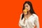 Vegetarian concept, Healthy woman eating yellow bell pepper standing in  orange background
