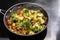 Vegetarian curry with broccoli and other vegetables in a steaming frying pan on a black stovetop, Asian cooking concept, copy