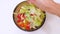 Vegetarian diet vegetable salad glass bowl. Female hand add salt