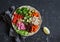 Vegetarian food bowl. Quinoa, beans, sweet potatoes, broccoli, peppers, olives, cucumber, nuts - healthy lunch. On the dark table