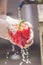 Vegetarian girl washes red pepper under running water