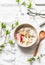 Vegetarian gluten free breakfast - quinoa, coconut milk, banana, apple, peanut butter bowl on light background, top view. Diet pla