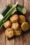 Vegetarian greek zucchini balls kolokithokeftedes close-up on a slate board. Vertical top view