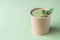 Vegetarian green cream soup in craft container for take away food decorated with mint and spices. Ecological individual package.