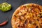 Vegetarian hot chili pizza on a wholemeal dough on a wooden Board near the ingredients, top view, close-up