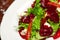 Vegetarian kitchen & healthy food concept. Fresh vegetable salad of sun-fried tomatoes, lettuce, beet and caprine cheese on white