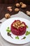 Vegetarian Lenten dish: a salad of beets with walnuts and garlic in a white plate in the shape of a circle