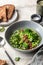 Vegetarian minestrone soup with green vegetables and lentils in gray plate on textured background