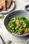 Vegetarian minestrone soup with green vegetables and lentils in gray plate on textured background