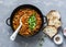 Vegetarian mushrooms chickpea stew in a iron pan and rustic grilled bread on a gray background, top view. Healthy vegetarian food