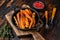 Vegetarian Oven baked sweet potato fries. Dark wooden background. Top view