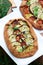 Vegetarian pies with vegetables and herbs on a stool against a background of green grass.