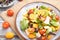 Vegetarian salad of pac choi cabbage, kiwi, tomatoes, kumquat, microgreen sprouts on gray wooden background. Top view, selective