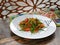 The vegetarian salad with vegetables, arugula and sprouted quinoa on white plate on wooden table.