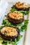 Vegetarian starter of grilled portobello mushrooms with cheese, herbs and garnished with rucola rocket leaves