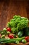 Vegetarian still life of fresh vegetables on wooden plate over rustic background, close-up, flat lay.