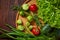 Vegetarian still life of fresh vegetables on wooden plate over rustic background, close-up, flat lay.